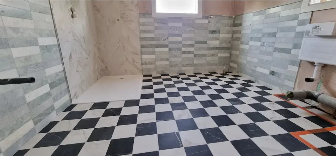 Wet room with a black and white checkerboard floor, level access shower tray and stone effect walls
